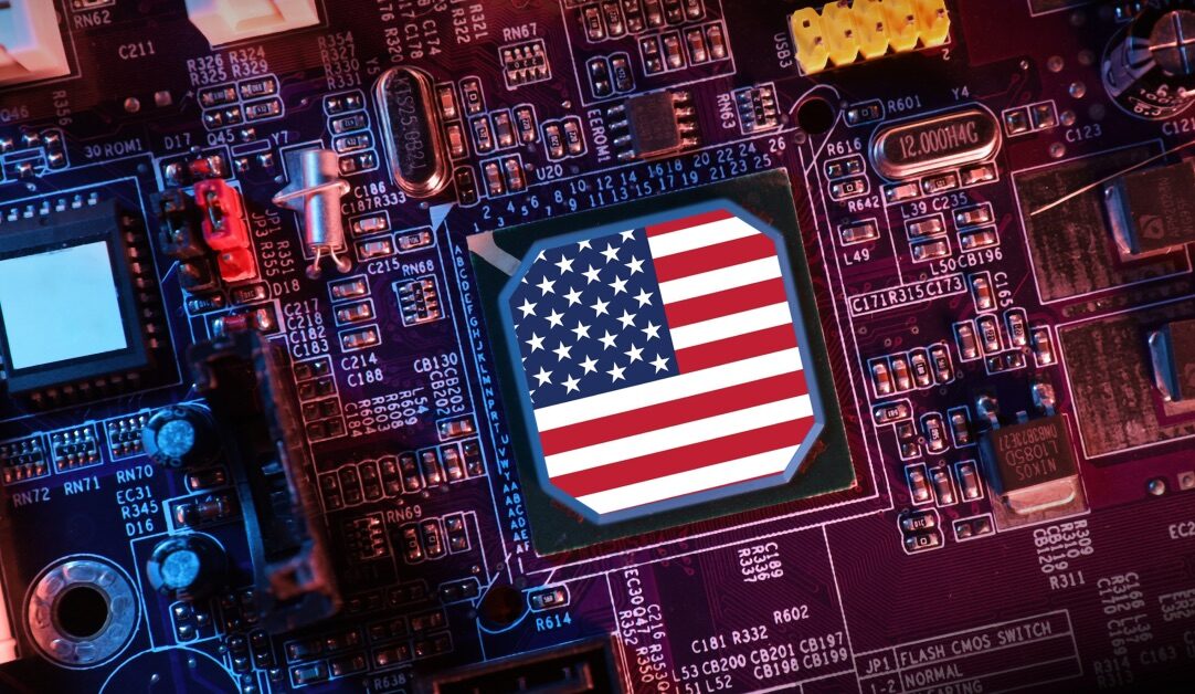 A computer motherboard with a central processor featuring an American flag design. The circuit board displays various electronic components and a red and blue color scheme.