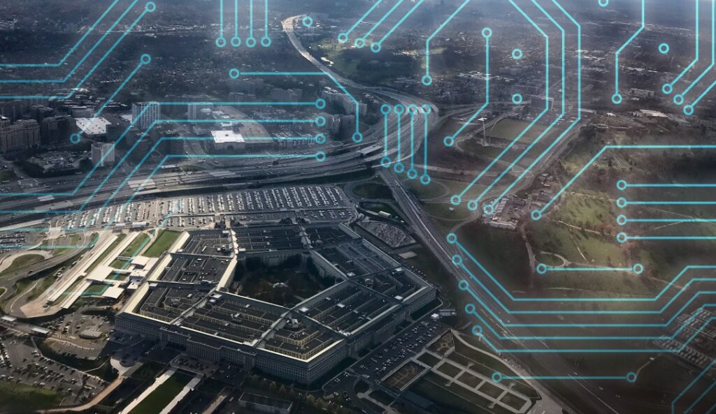 Aerial view of the Pentagon with superimposed blue circuit patterns overlaying the image. The surrounding area features highways and greenery, suggesting a connection between technology and defense infrastructure.